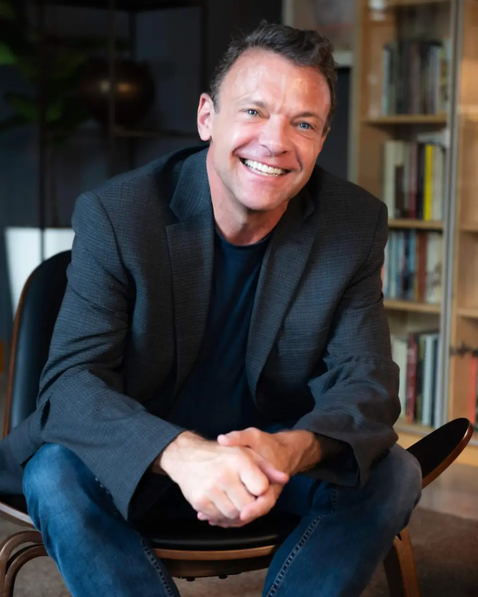 Dr. Scott Conkright smiling, seated in a chair in front of a bookshelf